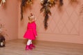 Two-year-old girl in bright pink dress pink shoes looks at vases with flowers Royalty Free Stock Photo