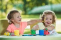 Two-year old girls painting with poster paintings together against green lawn Royalty Free Stock Photo