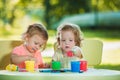 Two-year old girls painting with poster paintings together against green lawn Royalty Free Stock Photo