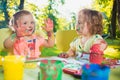 Two-year old girls painting with poster paintings together against green lawn Royalty Free Stock Photo