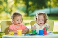 Two-year old girls painting with poster paintings together against green lawn Royalty Free Stock Photo