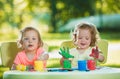 Two-year old girls painting with poster paintings together against green lawn Royalty Free Stock Photo