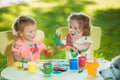 Two-year old girls painting with poster paintings together against green lawn Royalty Free Stock Photo