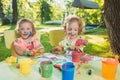 Two-year old girls painting with poster paintings together against green lawn Royalty Free Stock Photo