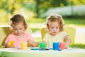 Two-year old girls painting with poster paintings together against green lawn Royalty Free Stock Photo