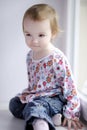 Two years old girl sitting by the window Royalty Free Stock Photo