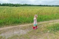 Two years old preschooler girl playing on farm dirt road near puddle