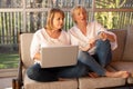 Two 55-year-old women in casual clothes use a laptop to shop online Royalty Free Stock Photo