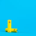 Two yellow AA alkaline batteries or NiMH rechargeable batteries on a blue background with space for text. Power elements