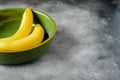 Two yellow bananas in a green bowl