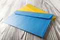 Two yellow and blue envelopes with letters on white wooden background. Blanks for the designer. Concepts, ideas for postal service Royalty Free Stock Photo