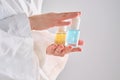 Two yellow and blue serums in a womans hands in a robe.