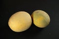 Two yellow Cantaloupe melons on black marble like board Royalty Free Stock Photo