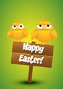 Two yellow chicks standing on a wooden Easter sign.