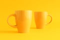 Two yellow coffee cups on yellow background