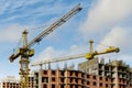 Two yellow construction cranes at the construction site of multi-storey brick houses against blue sky Royalty Free Stock Photo