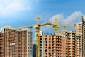 Two yellow construction cranes at the construction site of multi-storey brick houses against blue sky Royalty Free Stock Photo