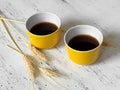 Two yellow cups with coffee and wheat spikes Royalty Free Stock Photo