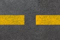 Two yellow dashed line of road markings close-up on the new bituminous asphalt road.