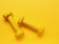 Two yellow dumbbells on a yellow background Royalty Free Stock Photo