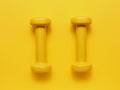 Two yellow dumbbells on a yellow background Royalty Free Stock Photo