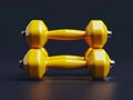 Two yellow dumbbells on a black surface