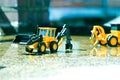 Two folk toys lined up on wet cement are depicted in bright colors.