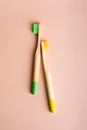 Two yellow and green eco friendly natural bamboo toothbrushes on pink background. Royalty Free Stock Photo