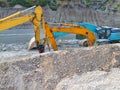 Two yellow and one blue excavators in the ditch at the site of the road construction works Royalty Free Stock Photo