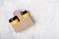 Two yellow paper cups in craft cup holder, light gray concrete background. Top view. Coffee to go. Copy space on the right. Place