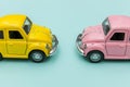 Two yellow pink vintage retro toy car isolated on blue pastel colorful background Royalty Free Stock Photo