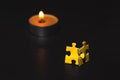 Two yellow puzzles standing against a candle.