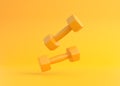 Two yellow rubber or plastic coated fitness dumbbells falling on yellow background