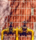 two yellow valves on the pipes on the wall of a tall building