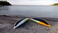 Two yellow, white and green canoes placed upside down on the beach to dry after a row Royalty Free Stock Photo