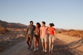 Two young adult couples walking on a desert road