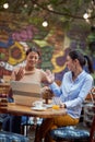 Two young adult women sitting in outdoor cafe, smiling, with palms  in the air preparing for high five Royalty Free Stock Photo