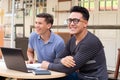 Two young adults laughing. Students at desk outdoors.