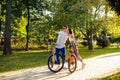 Two young adults are in the park with their bicycles. Attractive man in sunglasses is pointing his finger, showing something to Royalty Free Stock Photo