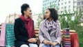 Two young african american women sharing their new purchases in shoppping bags with each other. Attractive girls talking