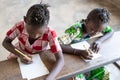 Two Young African Ethnicity Girls Writing in Desk at School Royalty Free Stock Photo