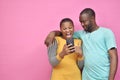 two young african friends, boy and girl, looking excited while viewing something on their smartphone together