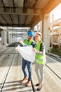 Two young architects visiting large construction site, looking at floor plans Royalty Free Stock Photo
