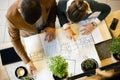 Two young architects discussing building plans during a meeting in an office