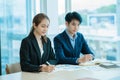 Two young Asian businessmen working together at the Financial Graph computer office. Share ideas, discuss and train business plans