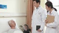 asian doctors informing senior patient of medical condition in hospital ward