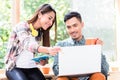 Two young Asian employees working together on a laptop in the of