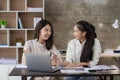 Two young Asian female accountants discuss working