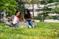 Two young Asian female college students are sitting on the grass in a park, using a laptop together Royalty Free Stock Photo