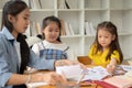 Two young Asian girls are enjoying studying English alphabet flashcards with a private teacher